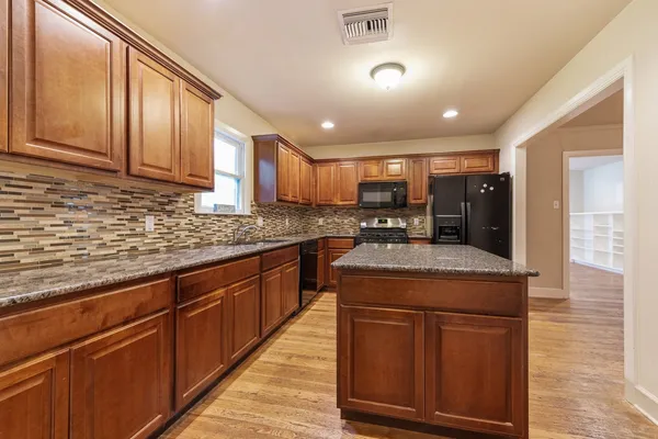 a kitchen with kitchen island granite countertop wooden cabinets and a sink