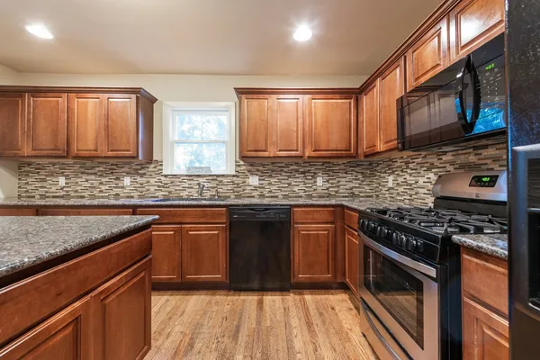 a kitchen with stainless steel appliances granite countertop wooden cabinets a stove top oven a sink and dishwasher