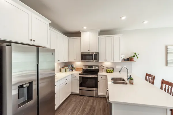 a kitchen with stainless steel appliances a refrigerator a stove a sink and white cabinets