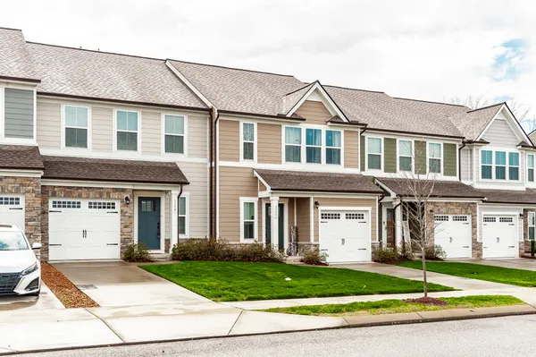 a front view of a house with a garden and trees