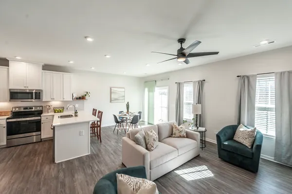 a living room with couches kitchen view and a stove