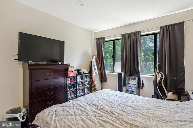 a bedroom with a bed and a flat tv screen on dresser