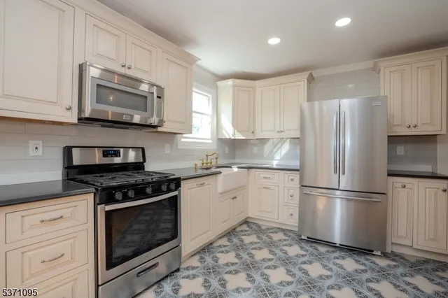 a kitchen with stainless steel appliances granite countertop a refrigerator stove a sink and a microwave