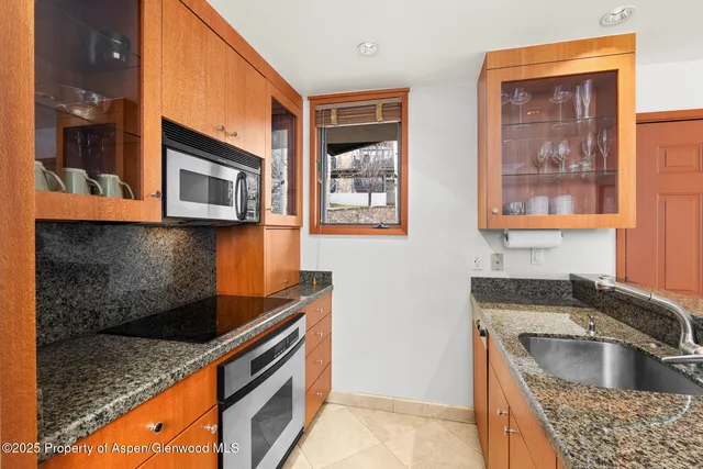 a kitchen with granite countertop a sink dishwasher stove and microwave oven