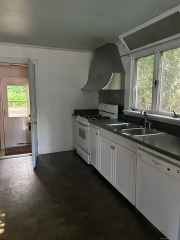 a kitchen with granite countertop a sink cabinets and a wooden floor