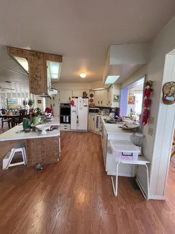a living room with stainless steel appliances kitchen island granite countertop furniture and a wooden floor