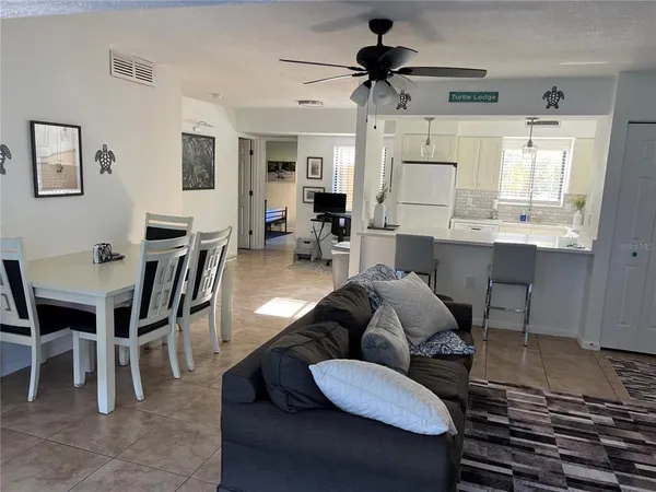 a living room with furniture a flat screen tv and kitchen view