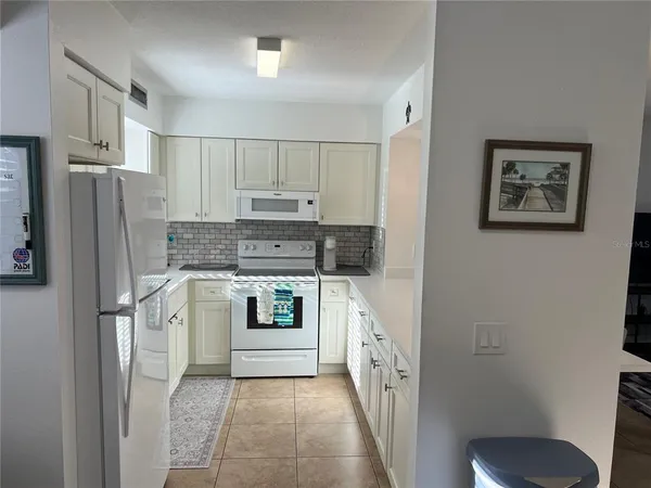 a living room with furniture kitchen view and a chandelier