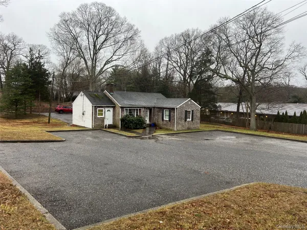 a front view of a house with large trees and playing ground