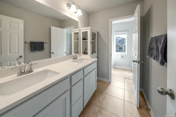 a spacious bathroom with a double vanity sink a mirror and shower