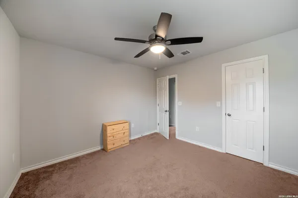 a view of an empty room and chandelier fan