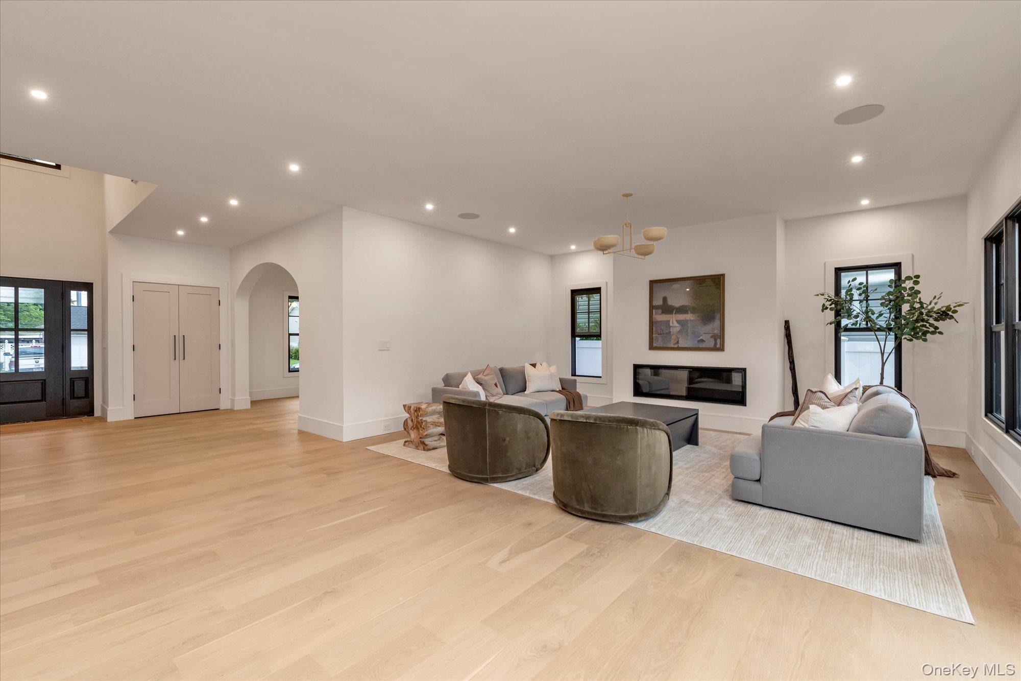1497 Carroll Street Wantagh, NY 11793 - Photo 3 of 18 Living room with light wood-style floors, arched walkways, recessed lighting, a chandelier, and a glass covered fireplace