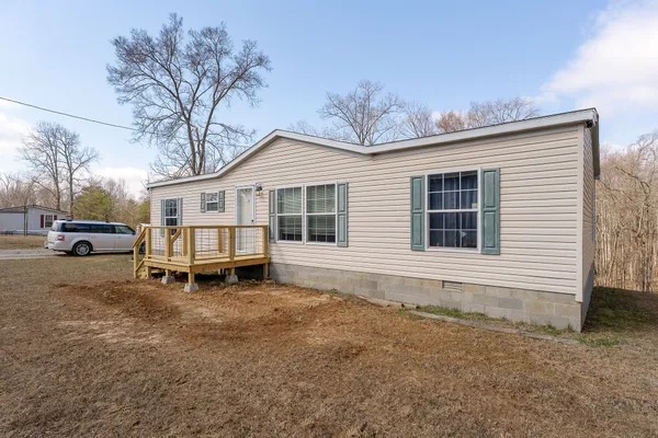 a white house that has a small yard and couches chairs with wooden fence