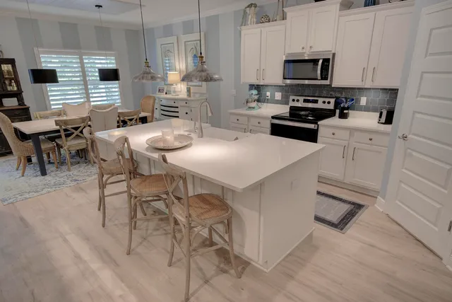 a kitchen with stainless steel appliances a stove a sink a microwave a refrigerator a stove a dining table and chairs with wooden floor