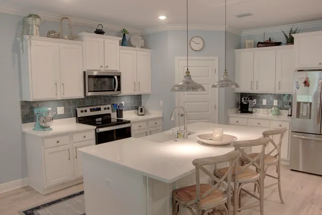 a kitchen with stainless steel appliances kitchen island granite countertop a sink a stove a refrigerator and cabinets