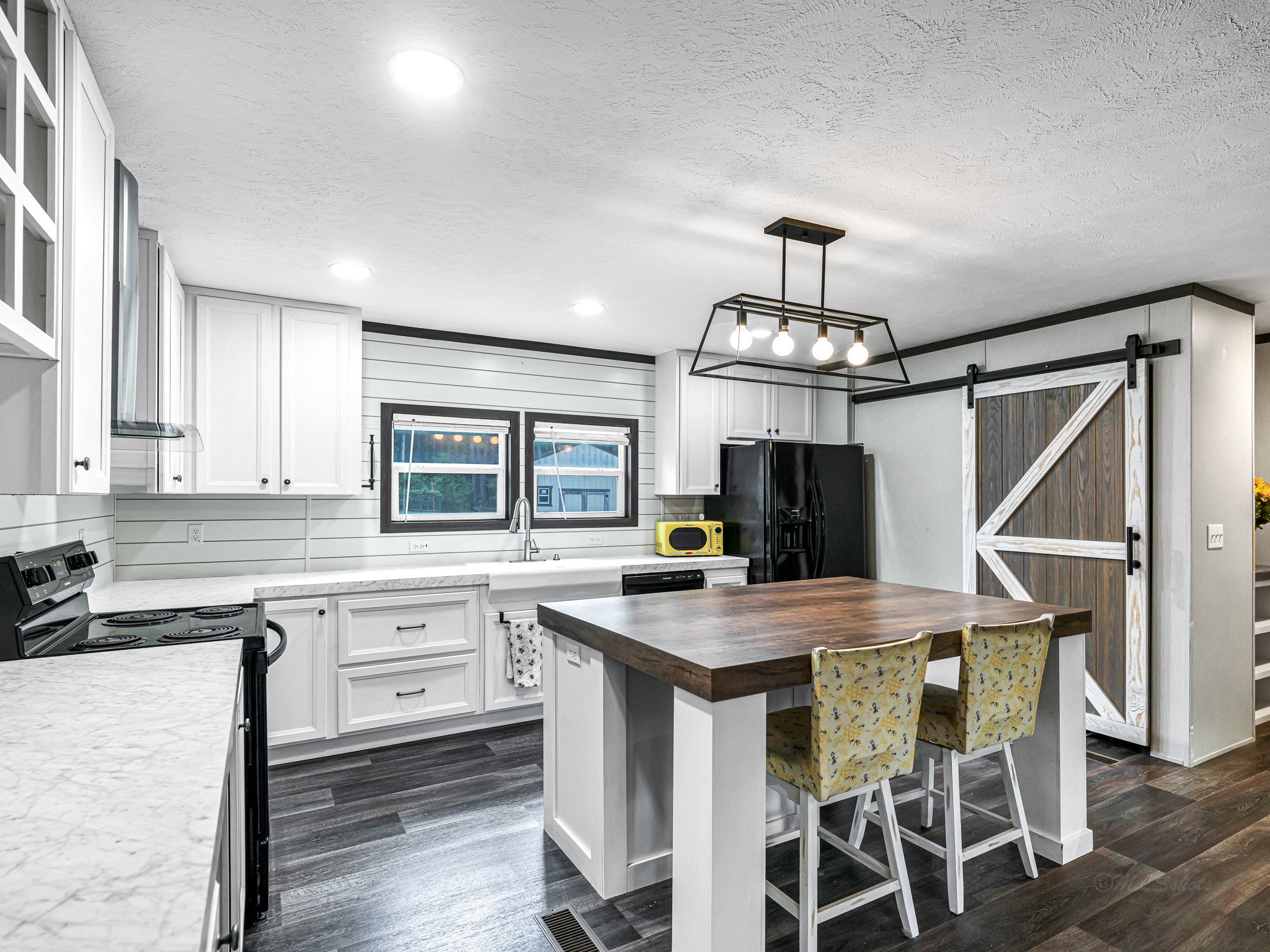 1047 Jimbob Lane New Ulm, TX 78950 - Photo 5 of 18 A stylish sliding barn door provides easy access to the hidden pantry while adding a modern farmhouse touch to the kitchen. A sleek, geometric chandelier hangs over the island, adding a sharp, modern edge to this great space!