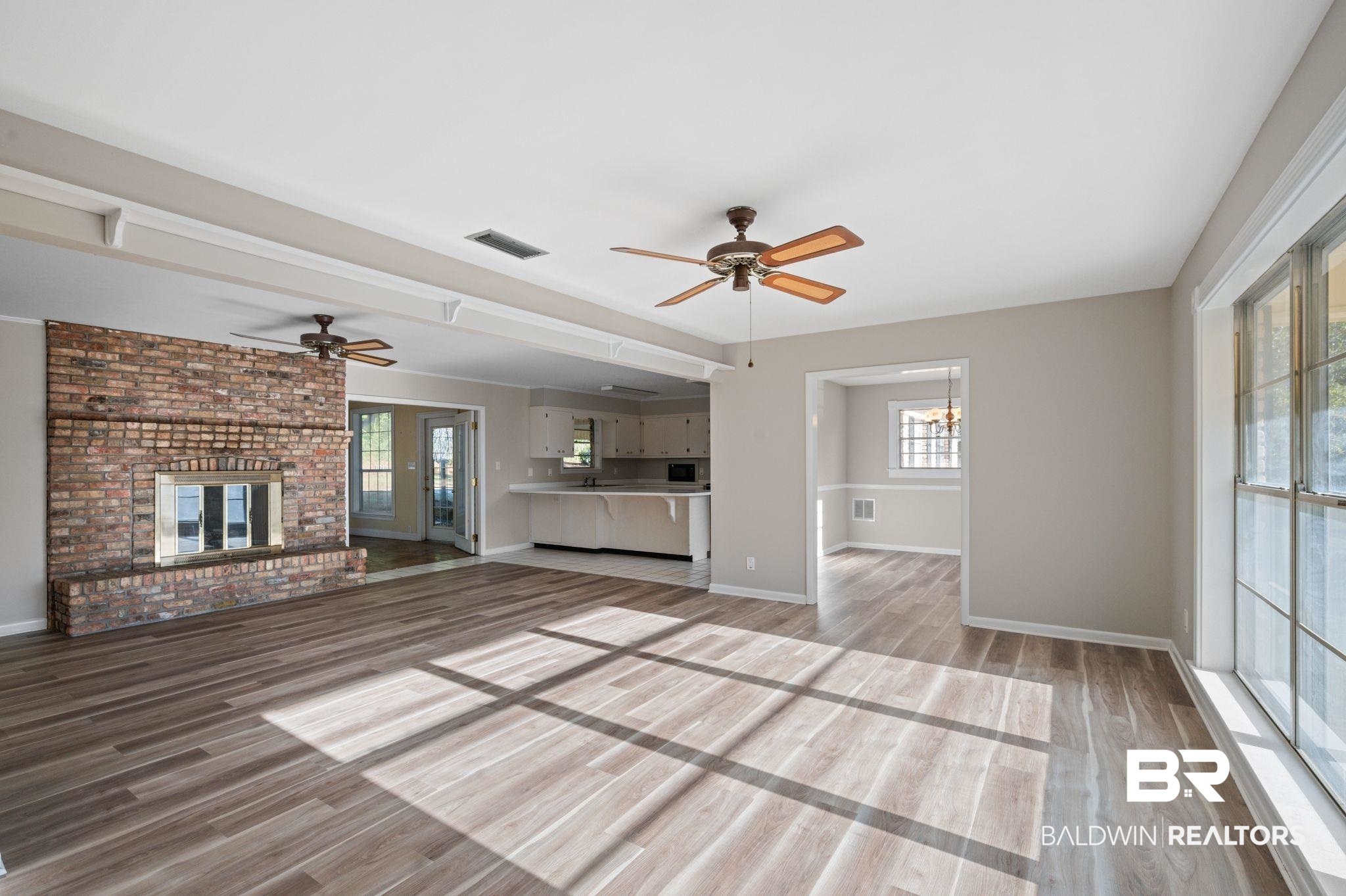 909 Caroline Avenue Daphne, AL 36526 - Photo 4 of 46 Unfurnished living room with hardwood / wood-style flooring, ceiling fan with notable chandelier, and a fireplace