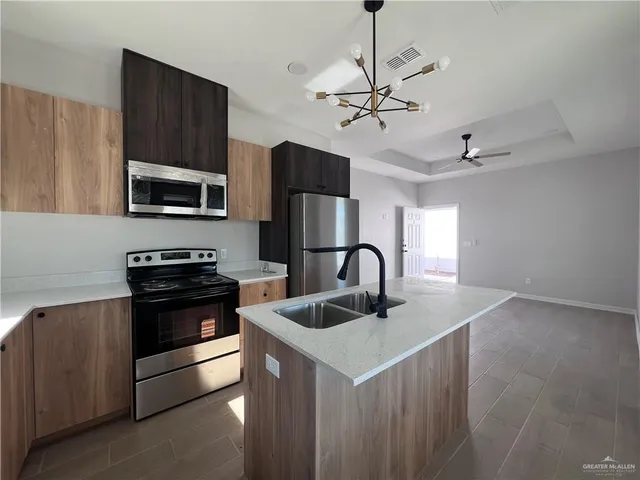 a kitchen with stainless steel appliances granite countertop a sink dishwasher a refrigerator a microwave oven with cabinets and wooden floor