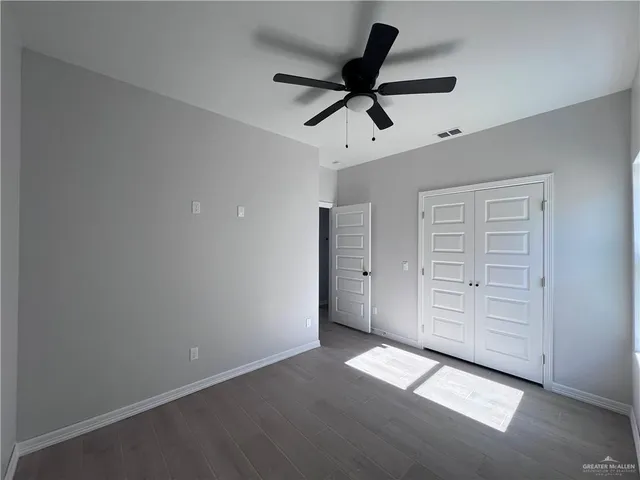 an empty room with closet and a ceiling fan