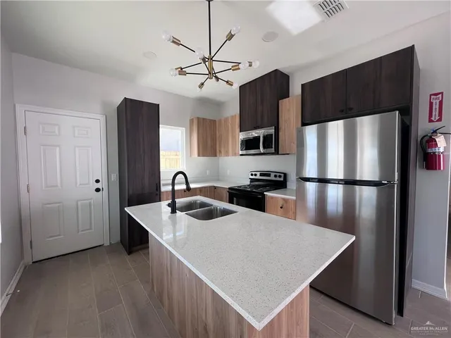 a kitchen with stainless steel appliances granite countertop a sink a refrigerator a stove a washer and dryer