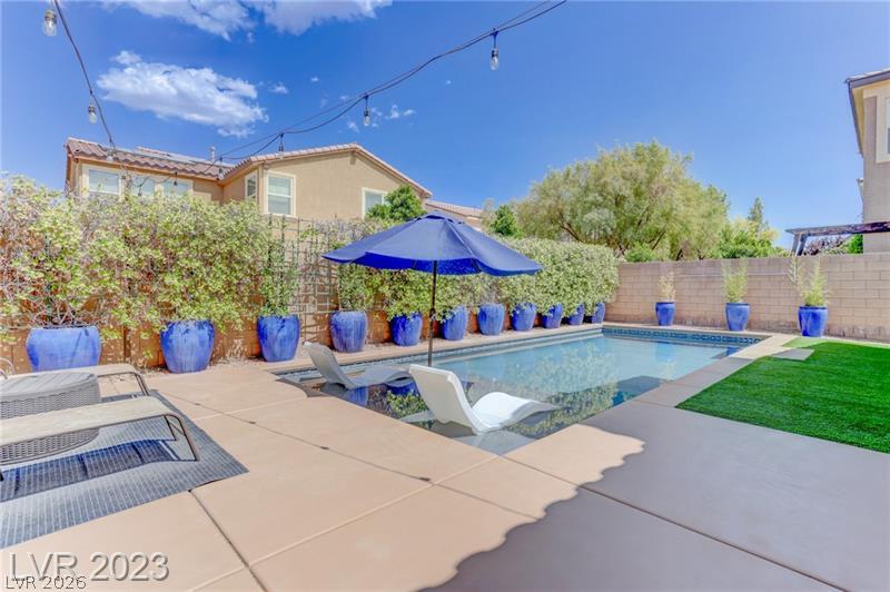 An inviting backyard oasis features a shimmering swimming pool surrounded by clean concrete decking.