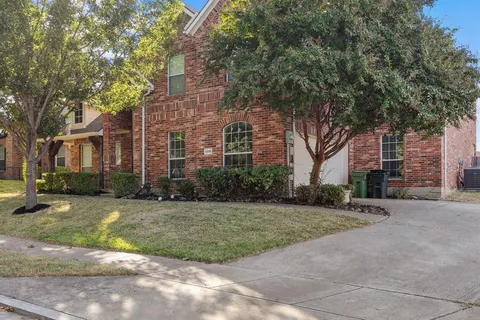 a view of a brick house with a big yard and large trees