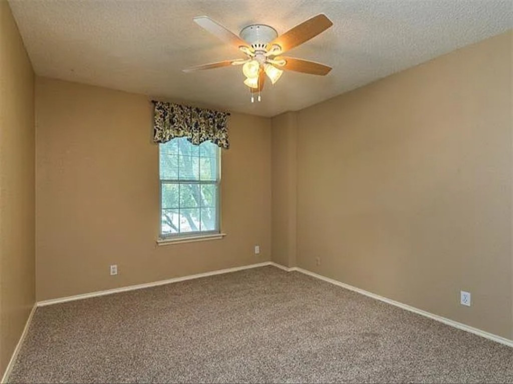 16303 Ascent Cove Pflugerville, TX 78660 - Photo 19 of 37 an empty room with a chandelier fan and windows