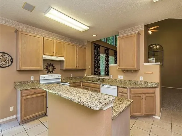 a kitchen with kitchen island granite countertop a sink stove and cabinets