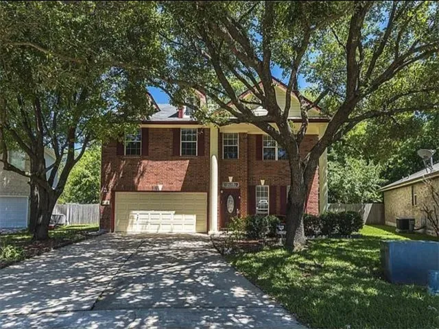 a front view of a house with a garden and tree