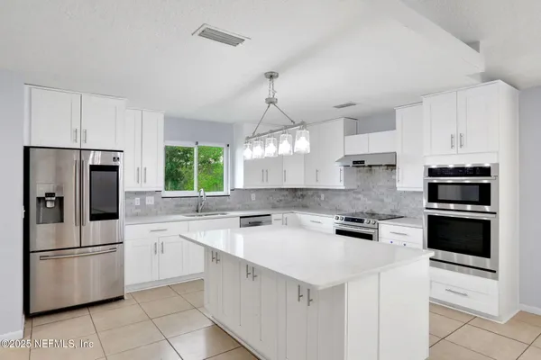 a kitchen with appliances a sink and cabinets
