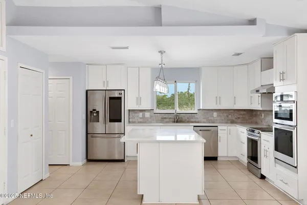 a kitchen with white cabinets and stainless steel appliances