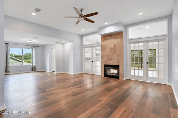 an empty room with windows a fireplace and wooden floor