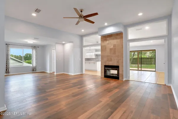 an empty room with wooden floor fireplace and windows