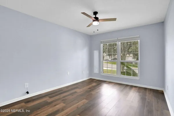 a view of an empty room with wooden floor and a window