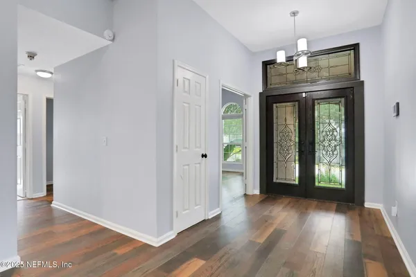 a view of a hallway with wooden floor and a chandelier