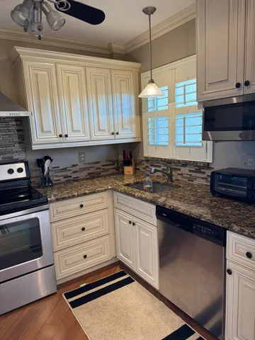 a kitchen with granite countertop cabinets stainless steel appliances and a sink