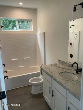a bathroom with a granite countertop sink toilet and shower