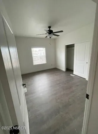 an empty room with windows and fan