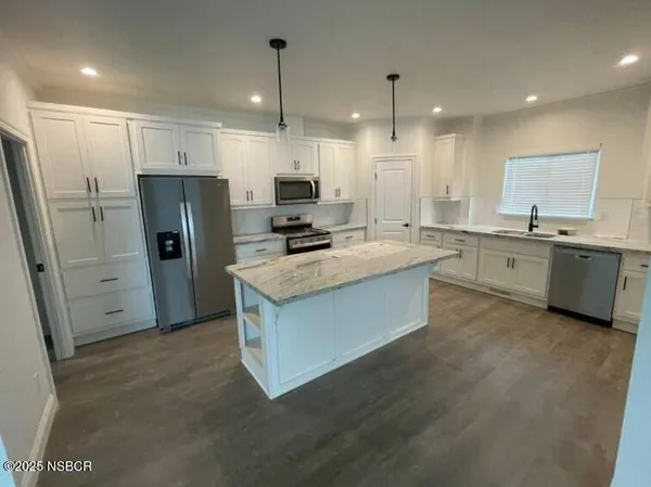 a kitchen with stainless steel appliances granite countertop a refrigerator a sink a stove and a oven