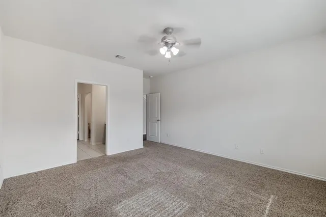 a view of an empty room with a chandelier fan