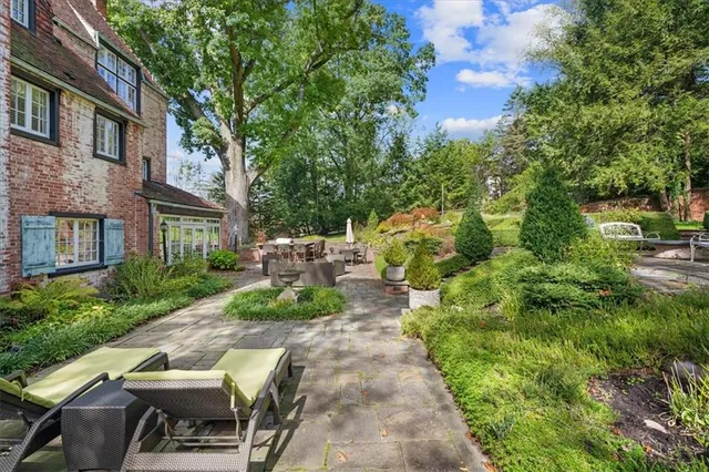 a lawn chairs sitting in a yard with plants and large trees