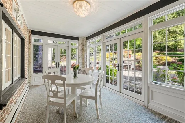 a dining room with wooden floor a chandelier a glass table and chairs