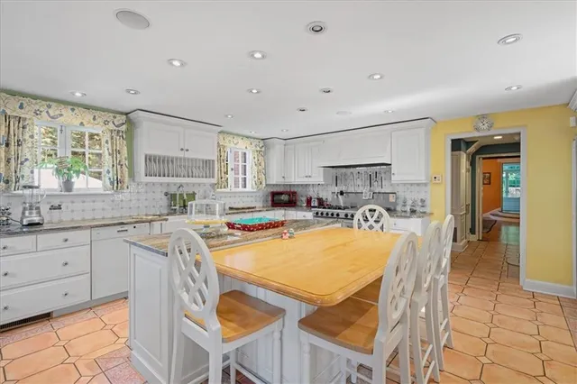 a kitchen with stainless steel appliances granite countertop a table chairs sink and cabinets