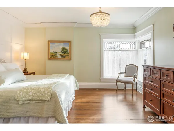 a bedroom with a bed and a table with wooden floor