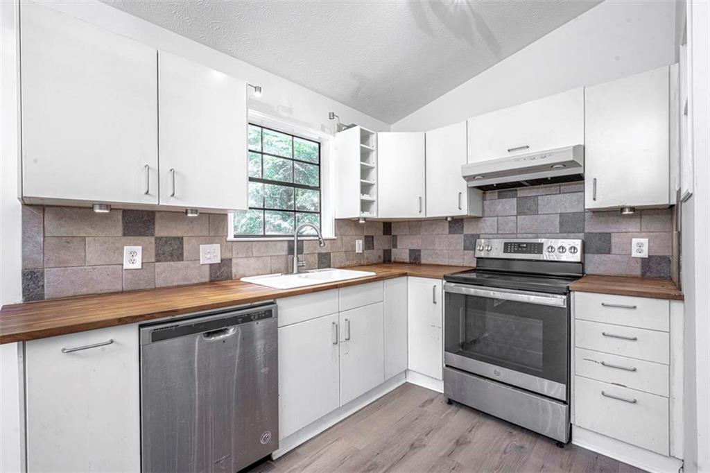 1752 Mitzi Court Duluth, GA 30097 - Photo 12 of 20 a kitchen with stainless steel appliances granite countertop a sink dishwasher a stove and a microwave oven with cabinets