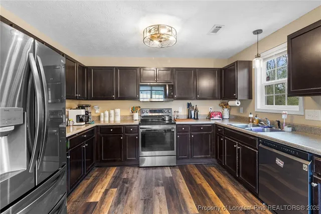 a kitchen with stainless steel appliances granite countertop wooden cabinets a sink dishwasher a stove and a refrigerator