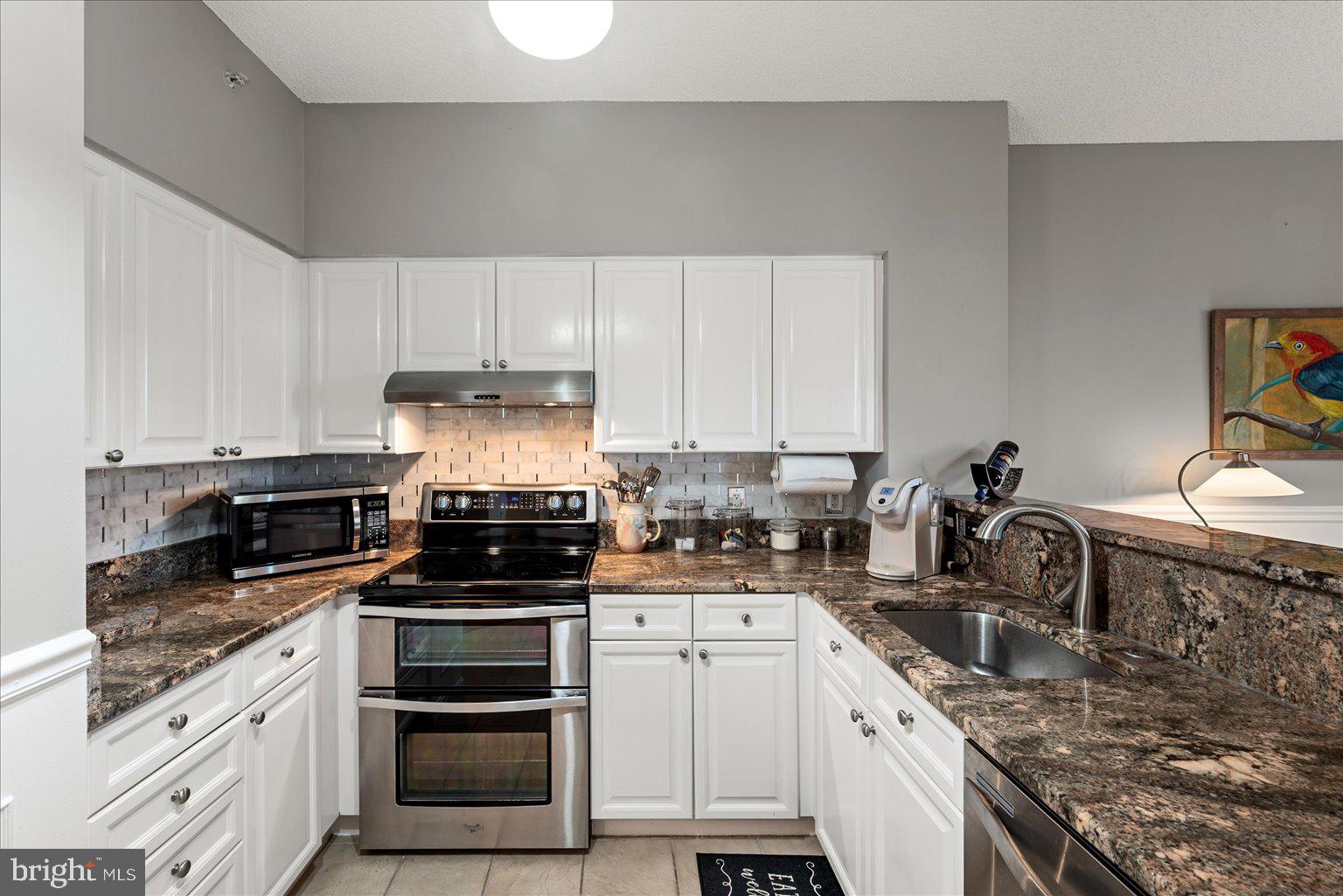 19375 Cypress Ridge Terrace, Unit 207 Leesburg, VA 20176 - Photo 14 of 44 a kitchen with a sink stove top oven and cabinets