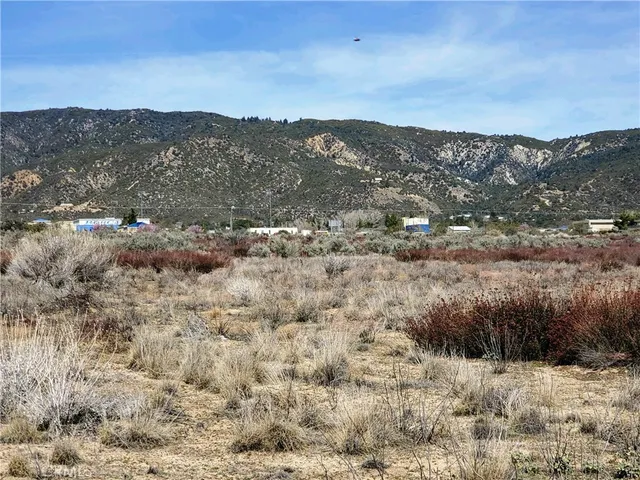 a view of a dry field with mountains in the background