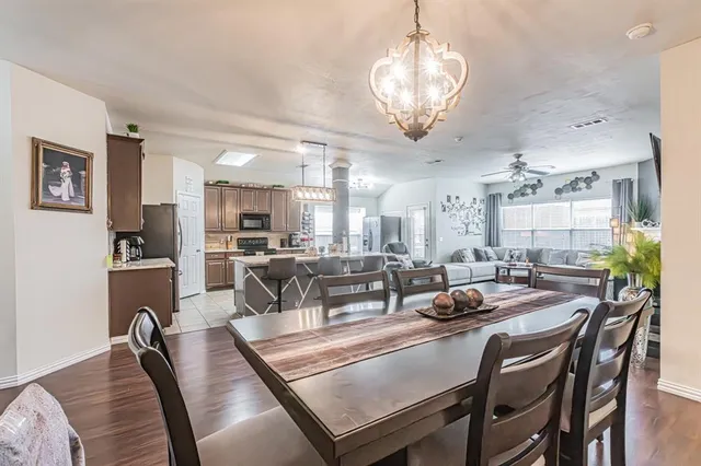 a dining room with wooden floor a chandelier a wooden table and chairs
