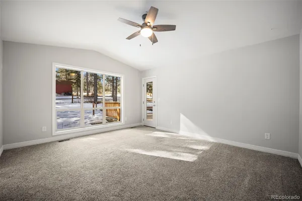 an empty room with chandelier fan and windows